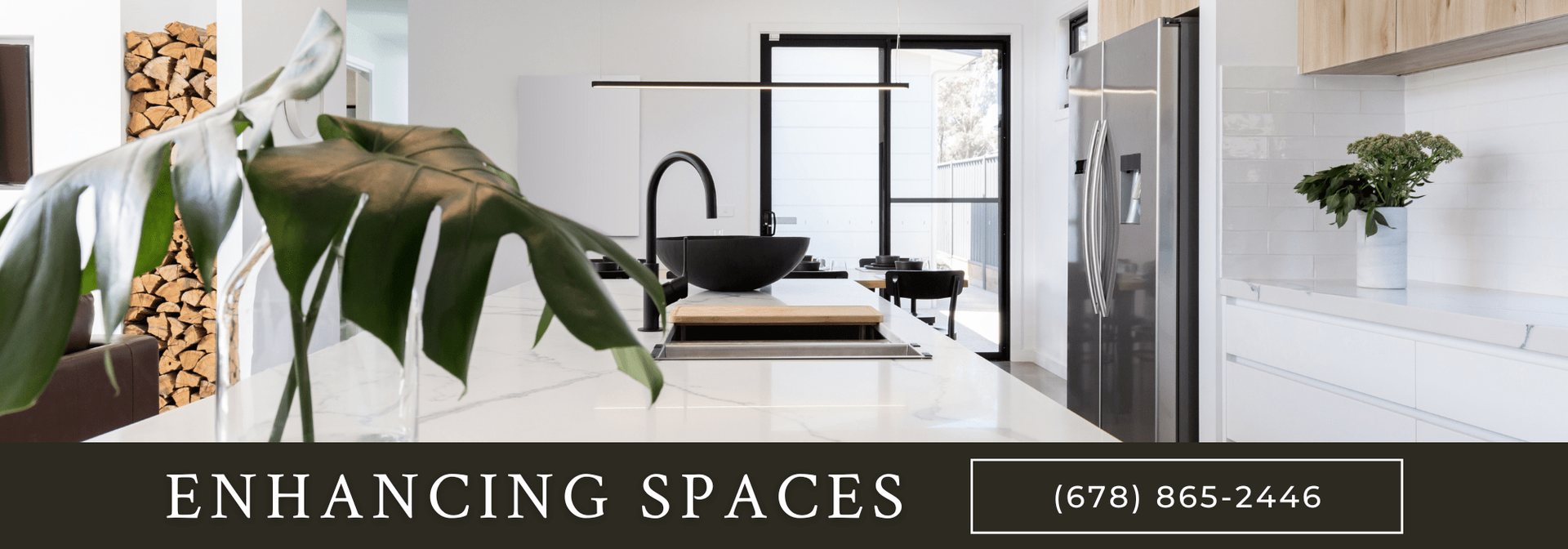 A modern, bright kitchen with a marble island, a black sink, and a plant in the foreground. Company: Enhancing Spaces.