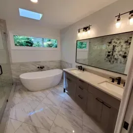 Modern bathroom with white marble tile floor, freestanding tub, double vanity, and large mirror.