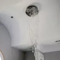 A modern flush-mount crystal chandelier hanging from a white ceiling.