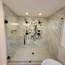 Modern walk-in shower with white marble-look tiles, a floral-patterned accent wall, and matte black fixtures.