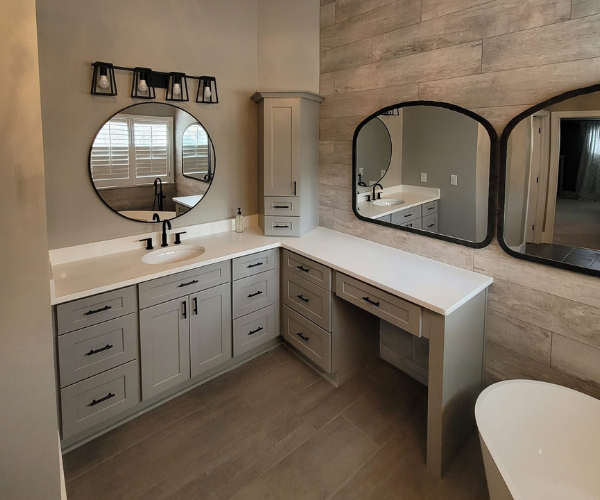 A bathroom vanity with gray cabinets, white counters, three mirrors, and a plank-style wood accent wall.