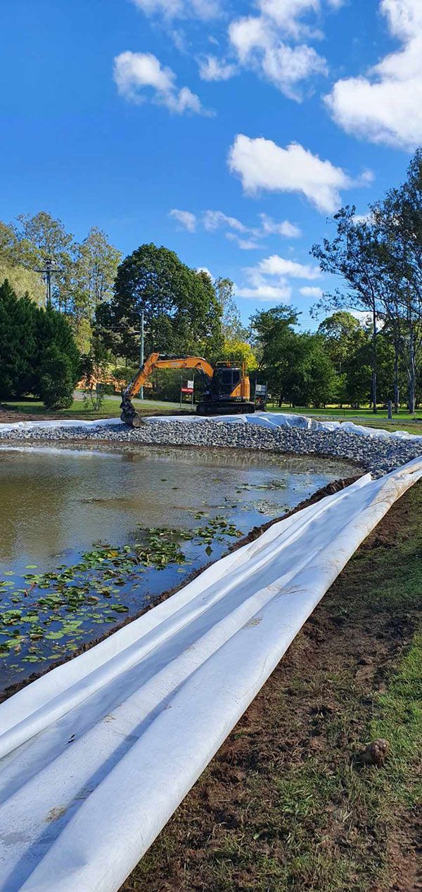 A large body of water with a large excavator in the background.