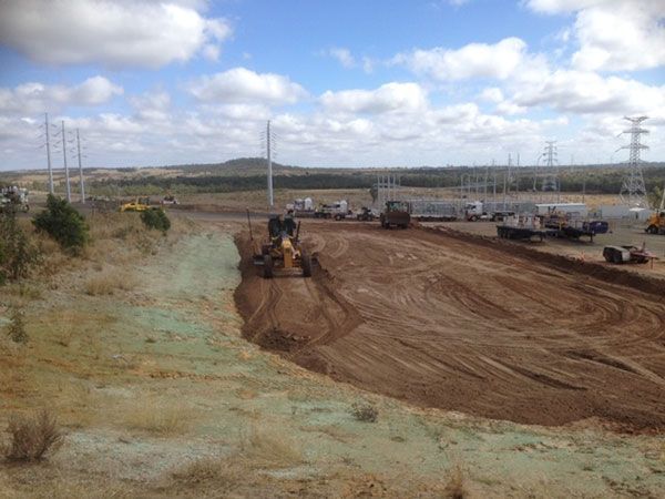 A large dirt road with a lot of trucks and tractors on it.