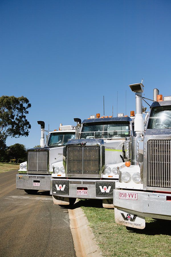 Three semi trucks are parked next to each other on the side of the road.