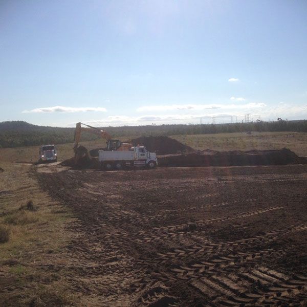 A dump truck is parked in the middle of a dirt field.