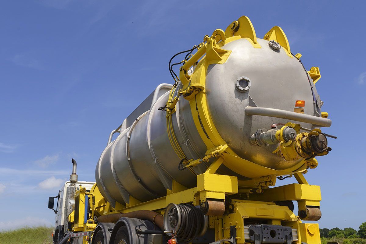A large yellow and silver tanker truck is parked in a field.