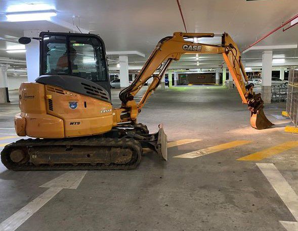 A small excavator is parked in a parking garage.