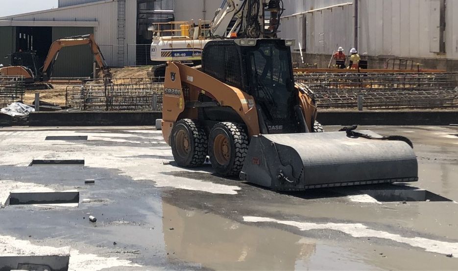 A bulldozer is driving on a wet concrete surface.