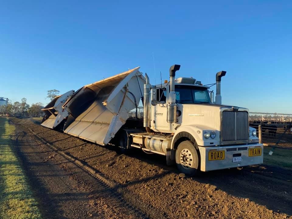 A white semi truck is parked on the side of a dirt road.