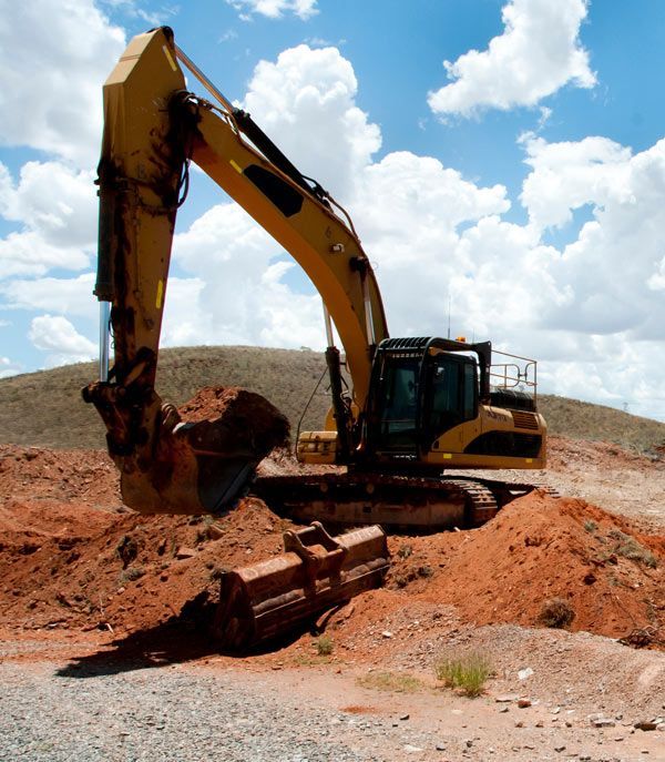 A yellow excavator is digging a hole in the dirt