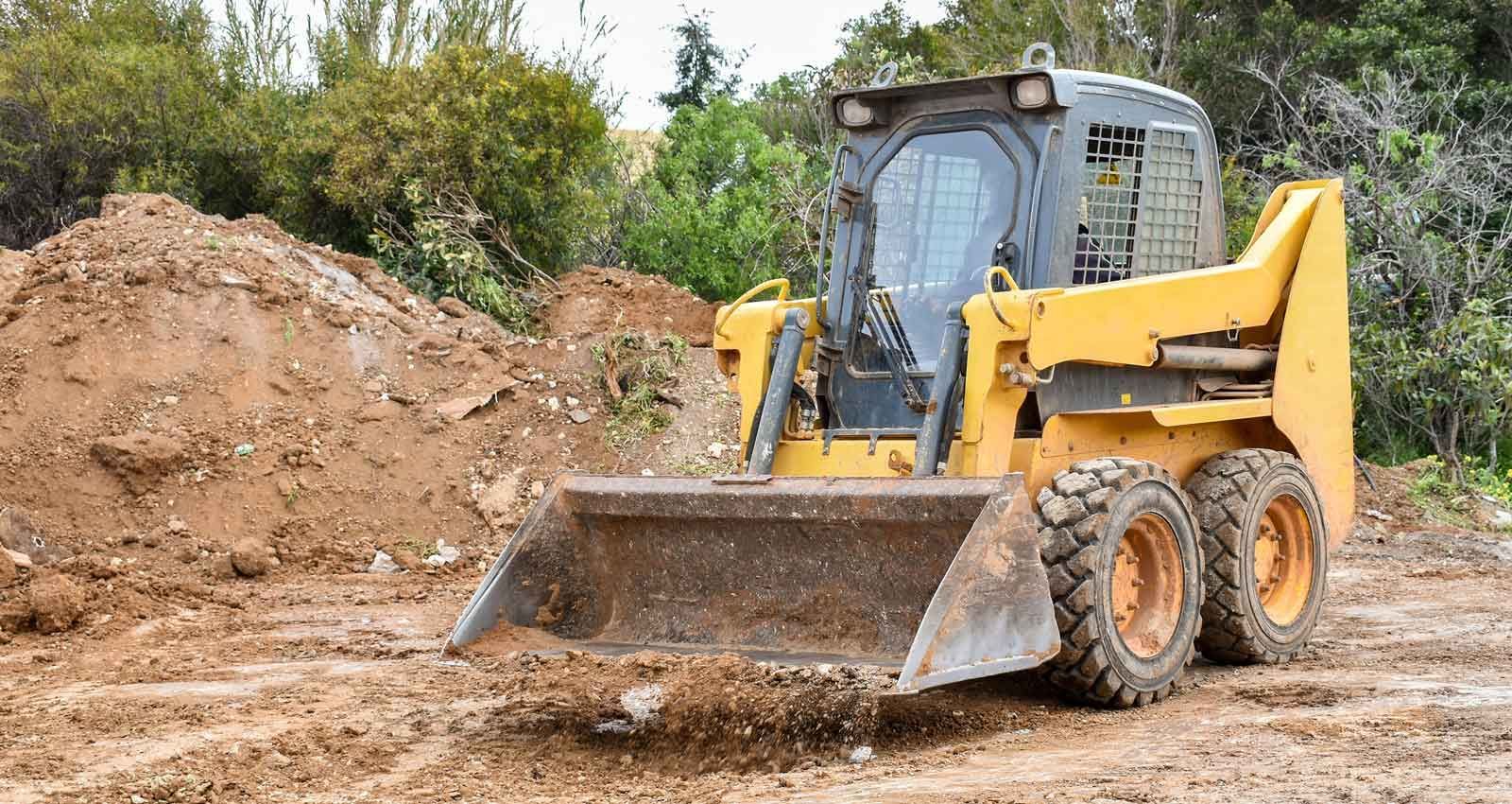 A yellow bulldozer is moving dirt on a dirt road.