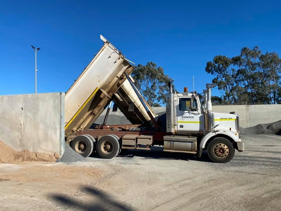 A white dump truck is parked in a dirt lot