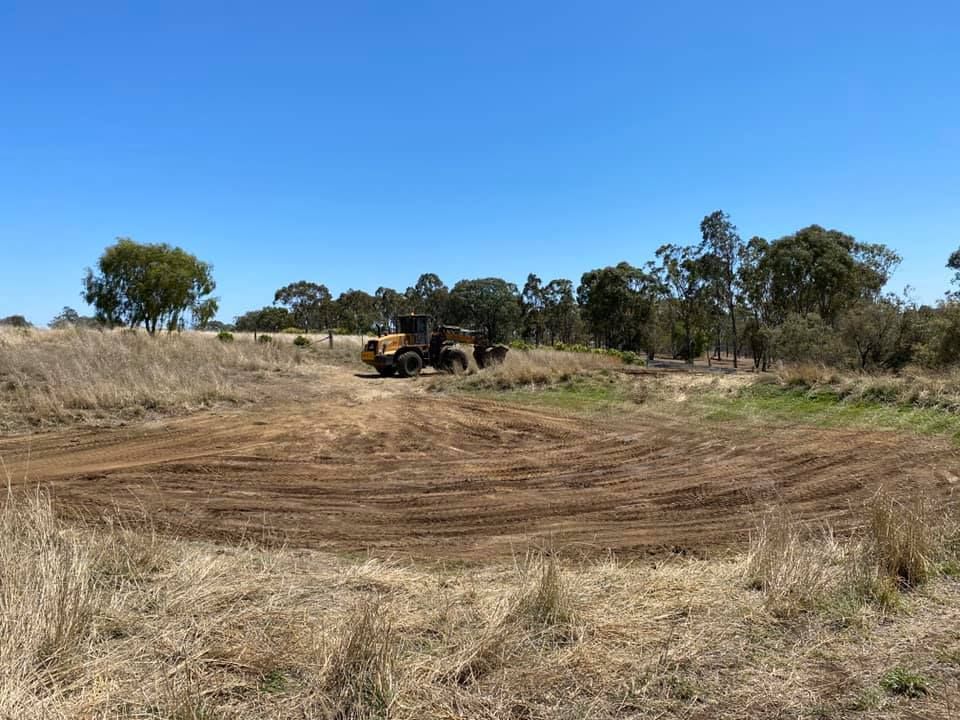 A bulldozer is driving through a dry grassy field