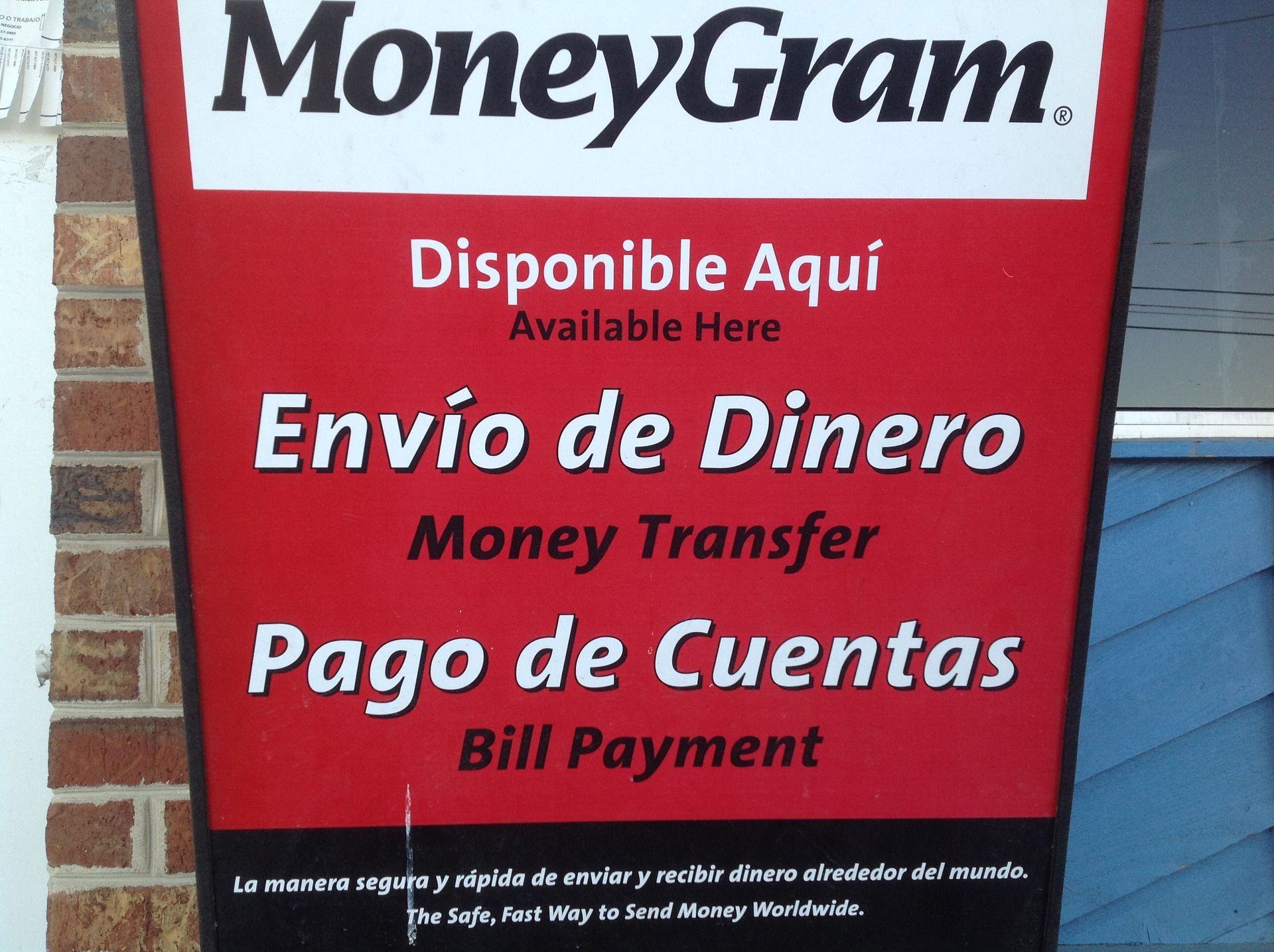 Sign for MoneyGram services: money transfer and bill payment. Red and white with Spanish and English text.