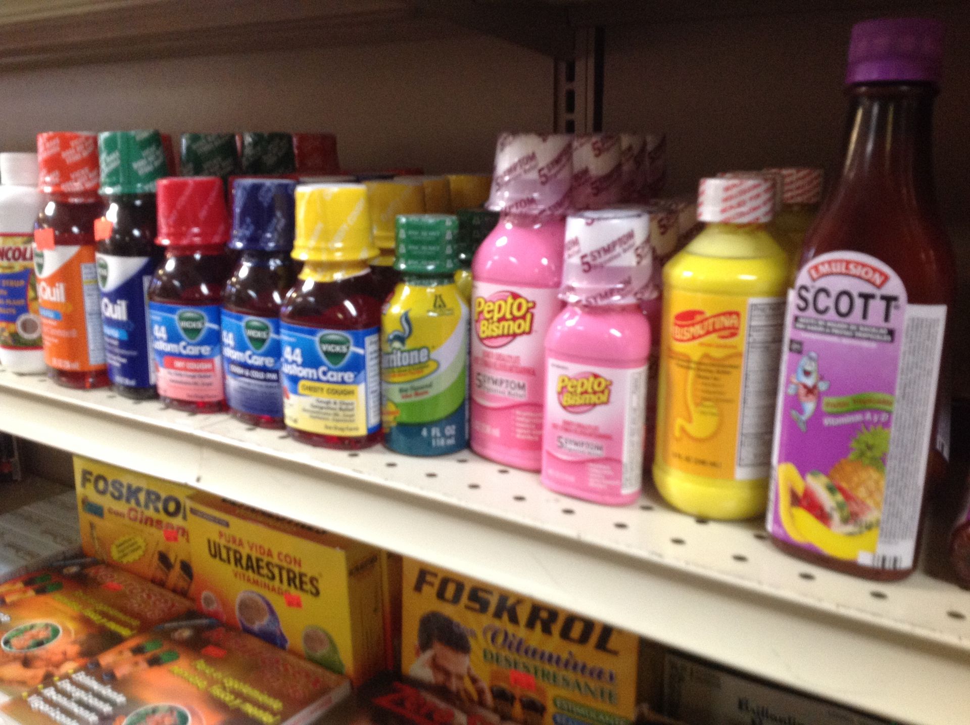 Shelves stocked with various cough syrups and medicine bottles, brightly colored, in a store.
