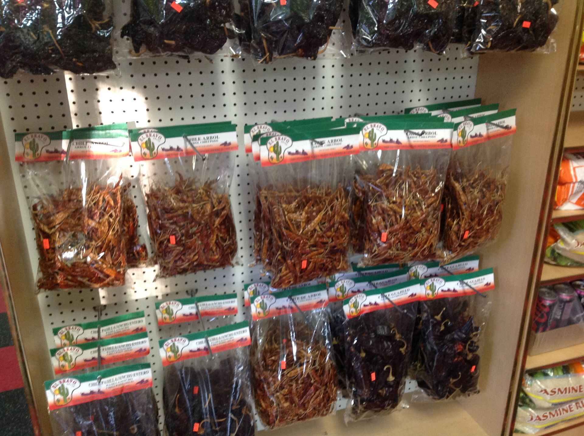 Bags of dried chili peppers in a store. Several varieties in clear plastic, arranged on a display shelf.