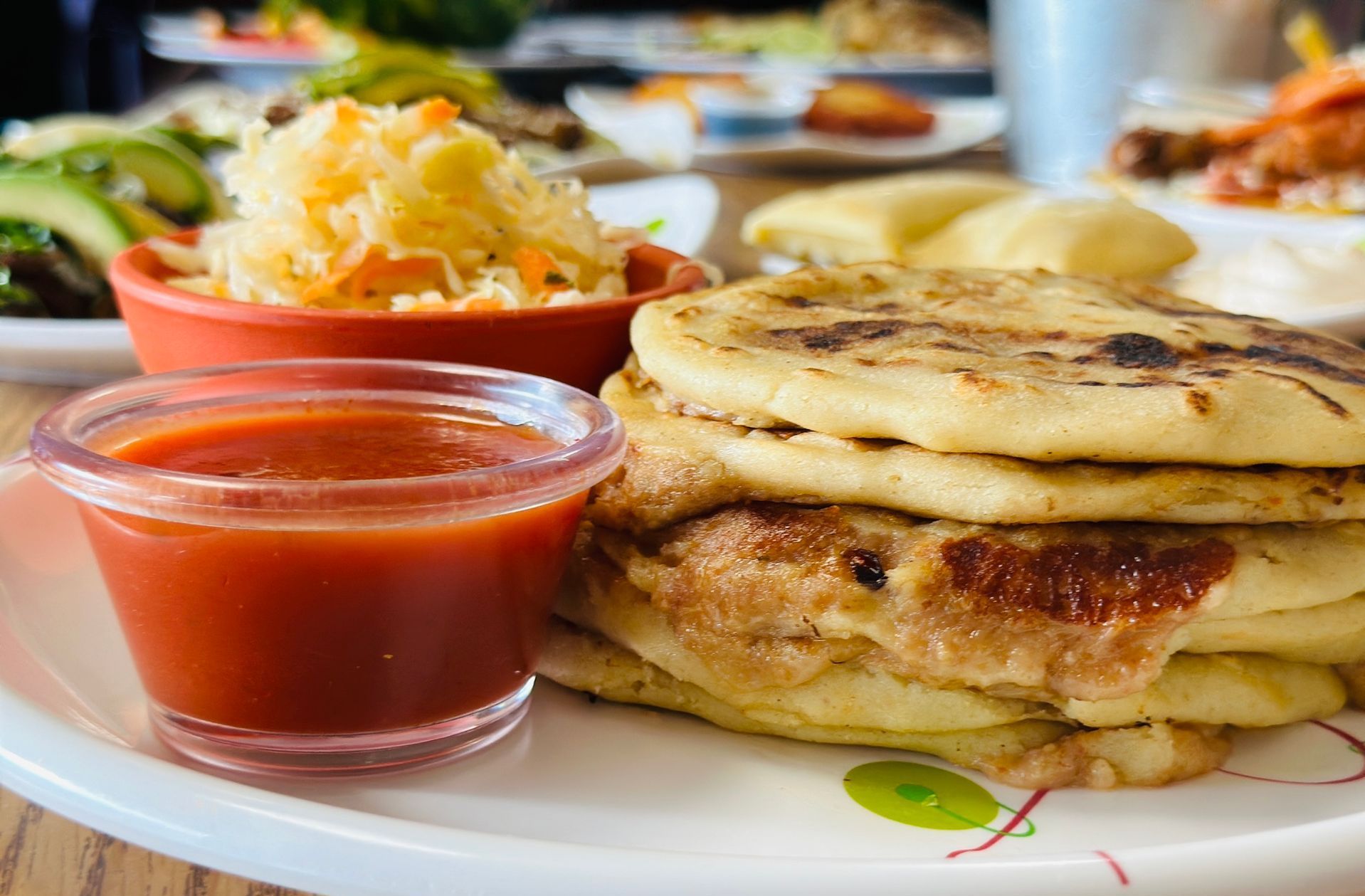Plate of pupusas with red sauce and curtido.