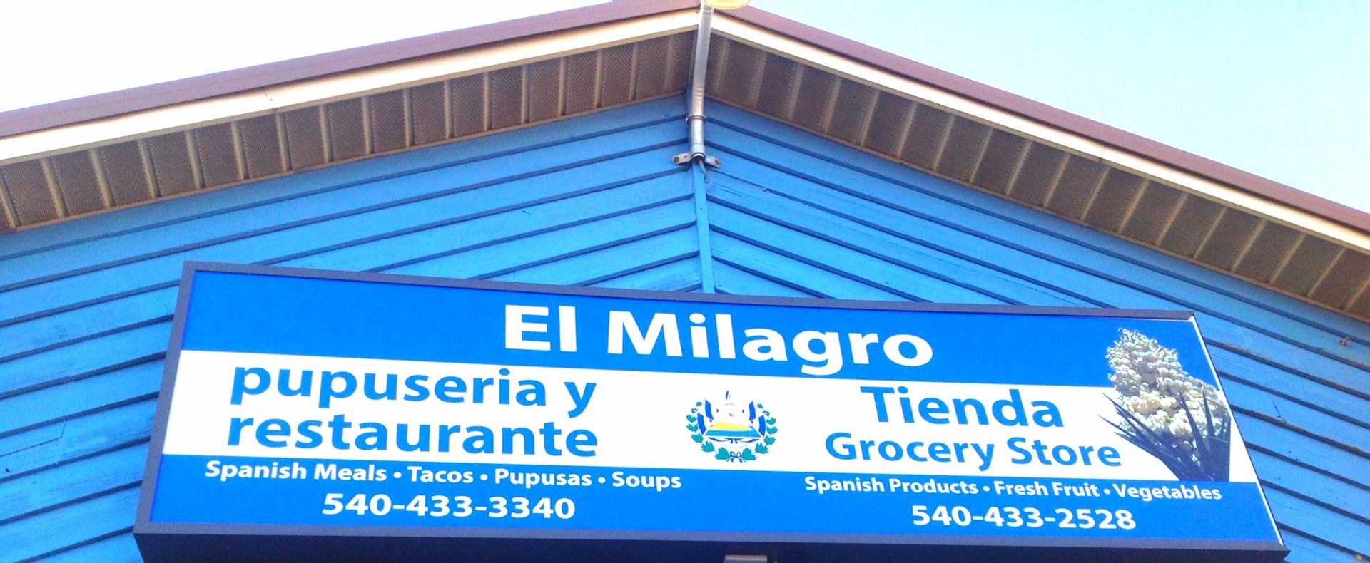 Blue El Milagro sign for pupuseria, restaurant, and grocery store.