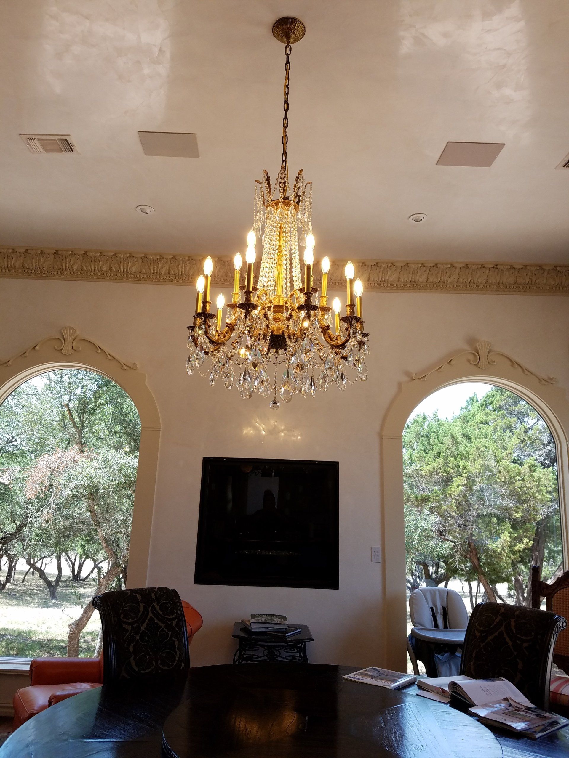 Fancy Chandelier installed flanked by two tall ornate windows.