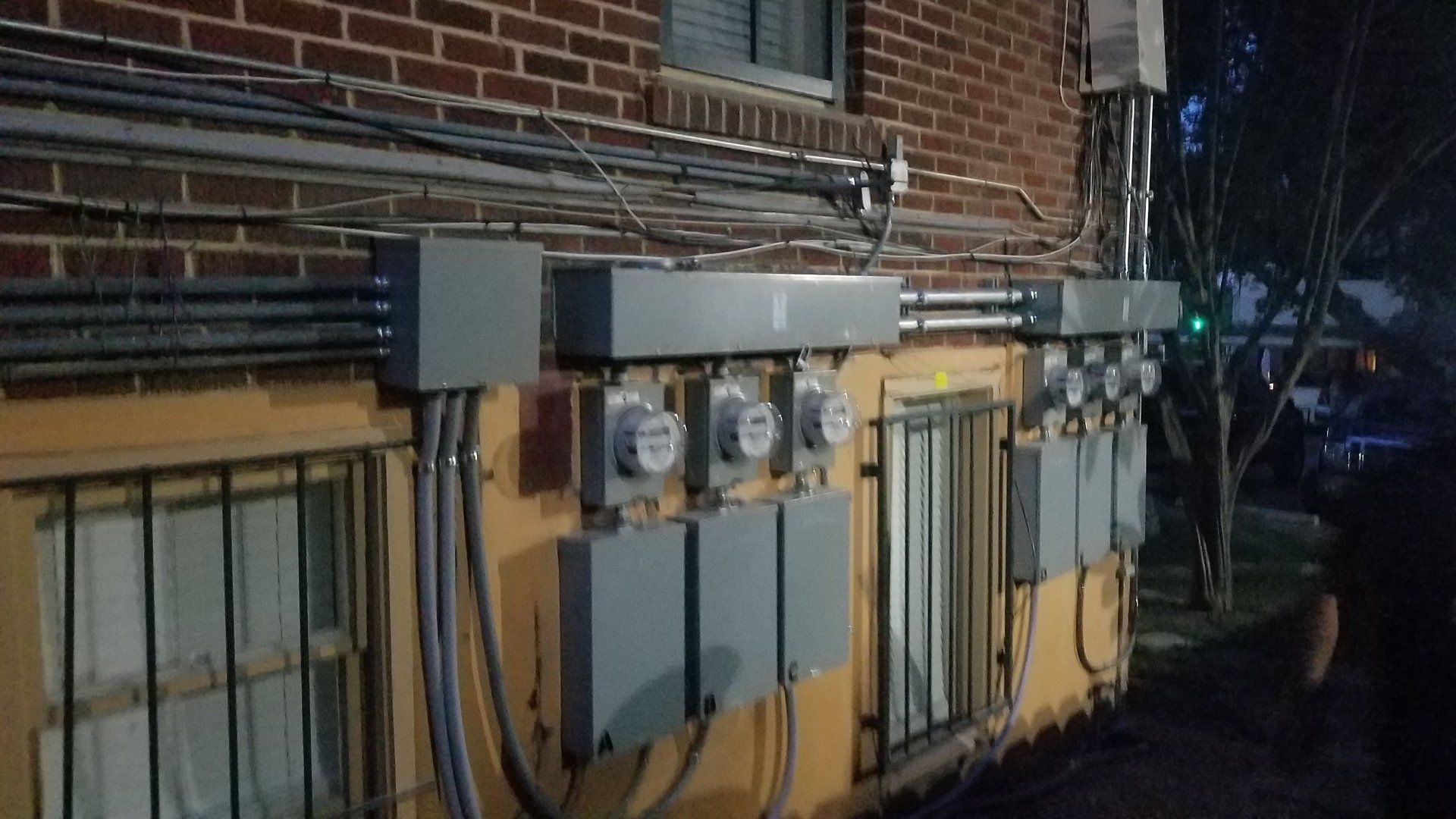 Several electrical enclosure boxes and conduit on the side of a multi residential building.