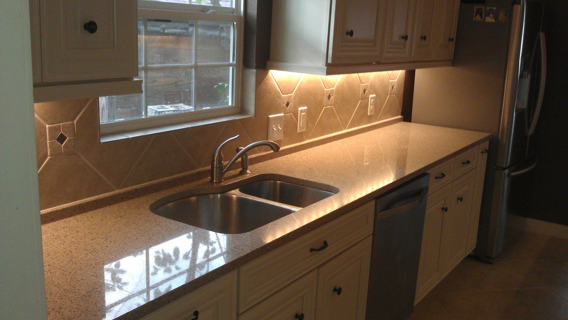 Different angle of white kitchen cabinets with hardwired puck lighting under the cabinets.