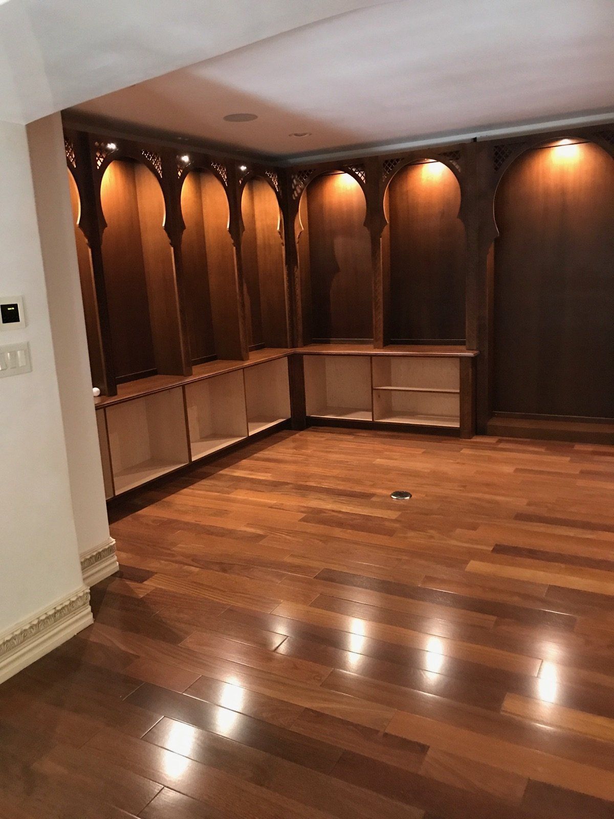 Interior of a room with wooden cabinets and shelves accented with ambient lighting.