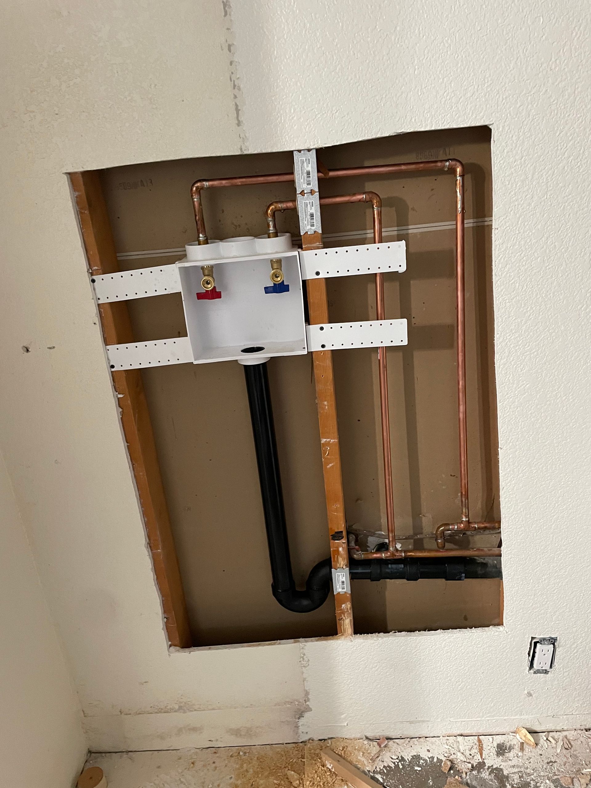 A hole in the wall with copper pipes coming out of it.