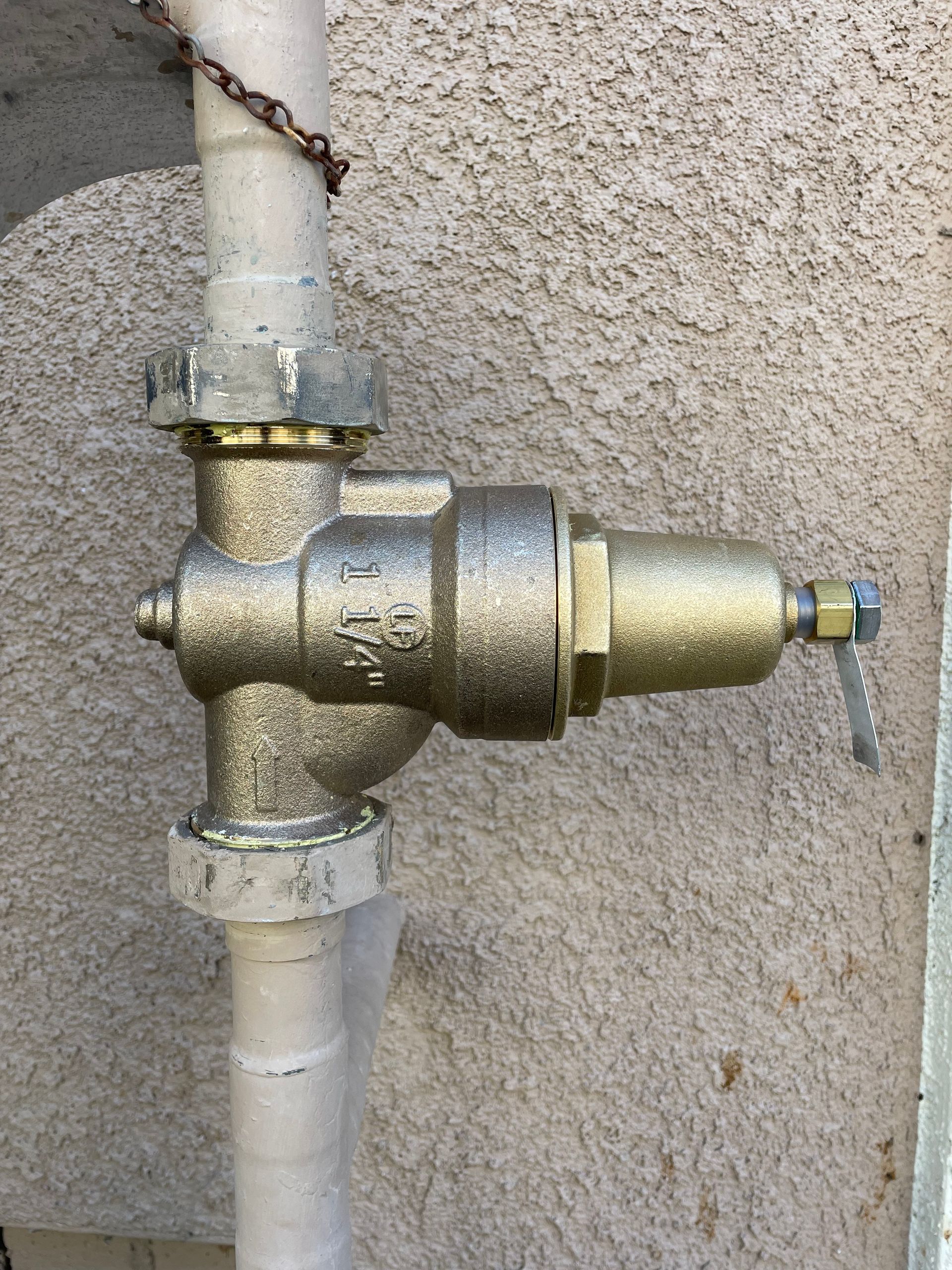 A close up of a valve on a pipe on a wall.