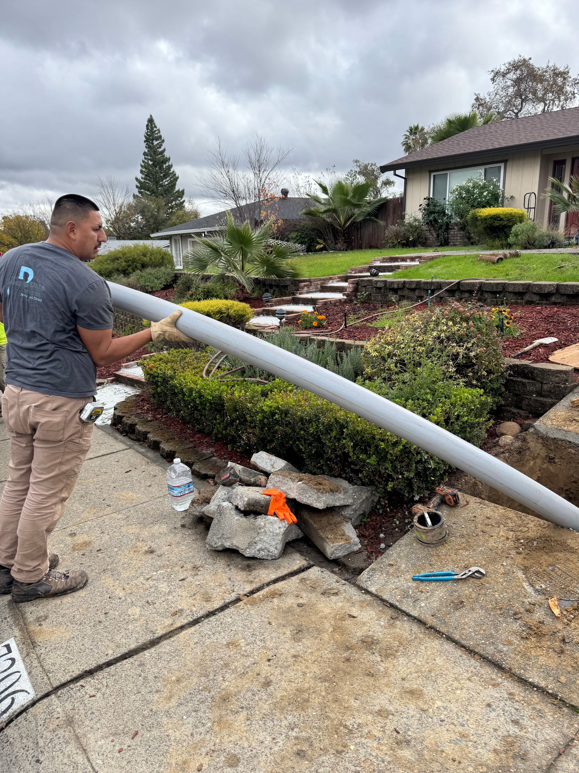 A man is standing on a sidewalk holding a large pipe.