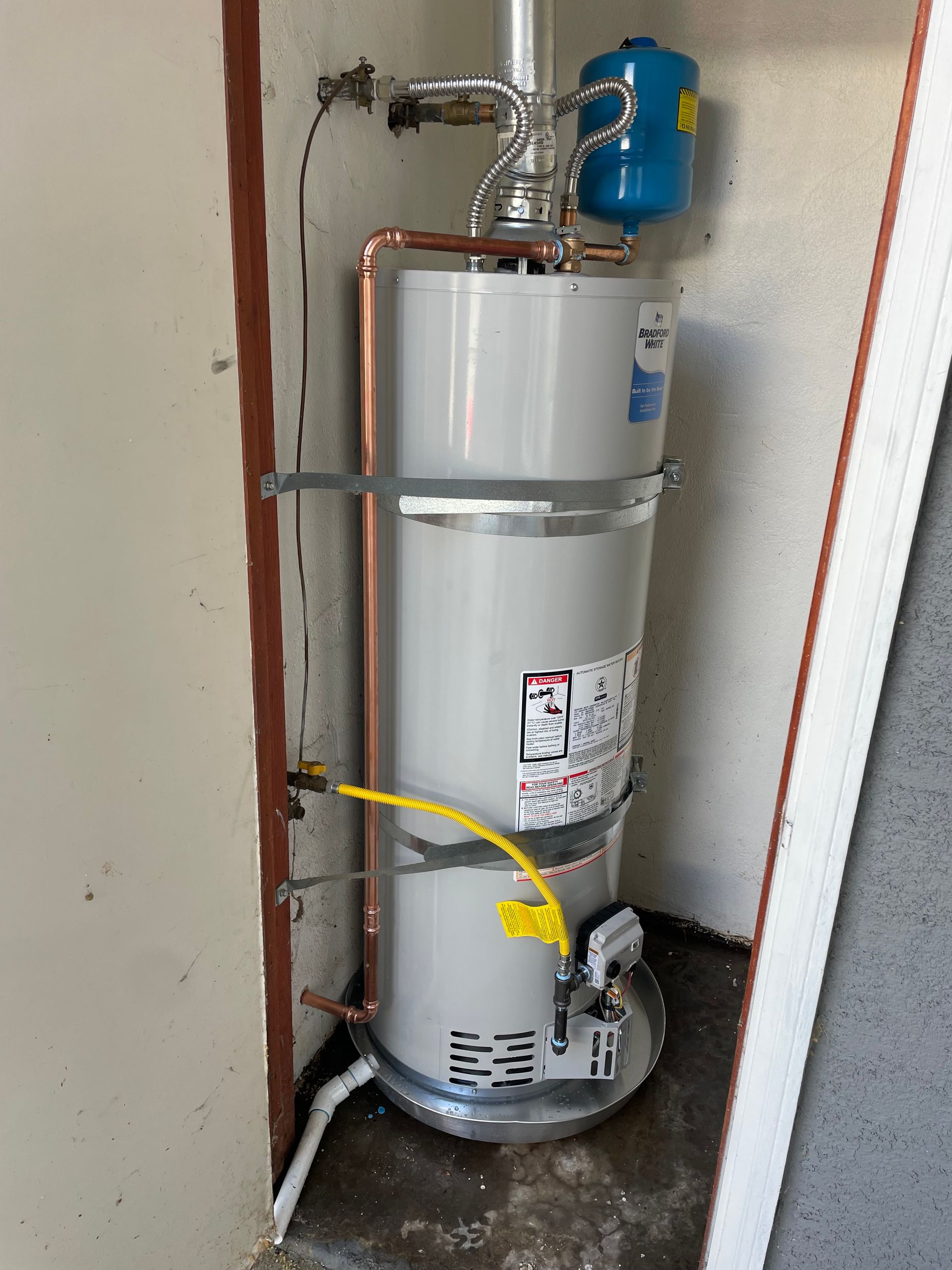 A water heater is sitting in a corner of a room.
