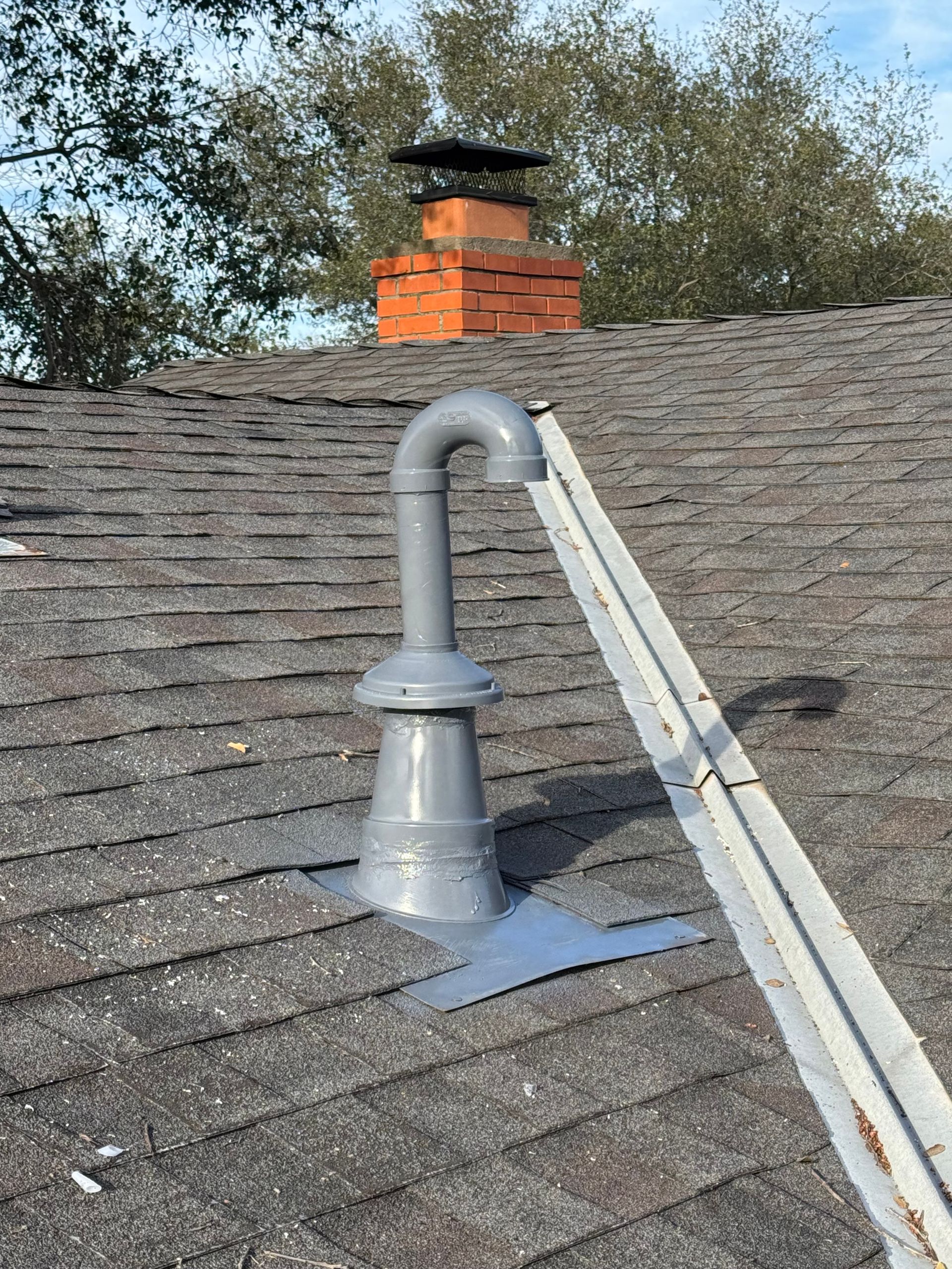 A roof with a chimney and a pipe on it.
