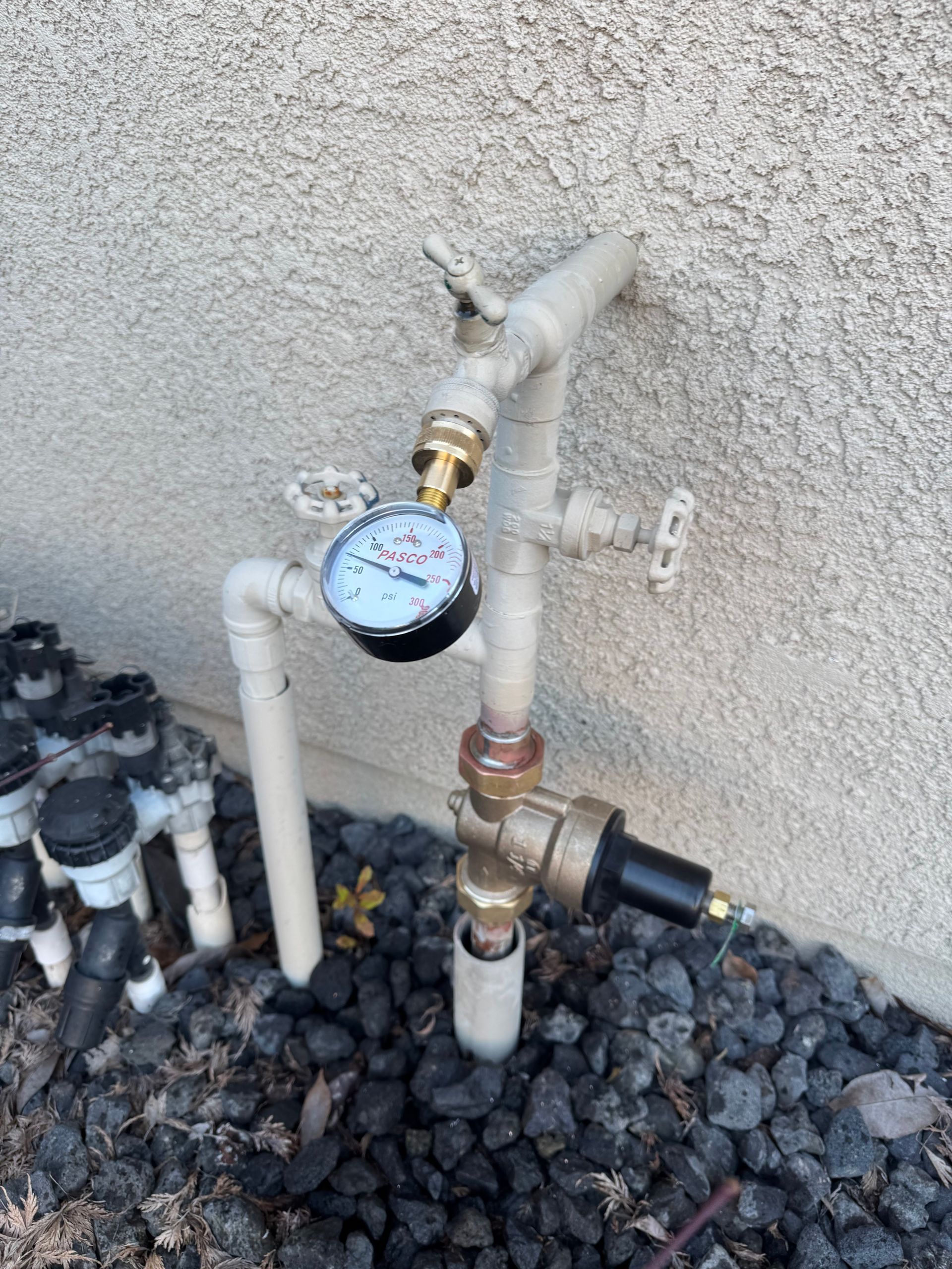 A water pressure gauge is attached to a pipe outside of a building.
