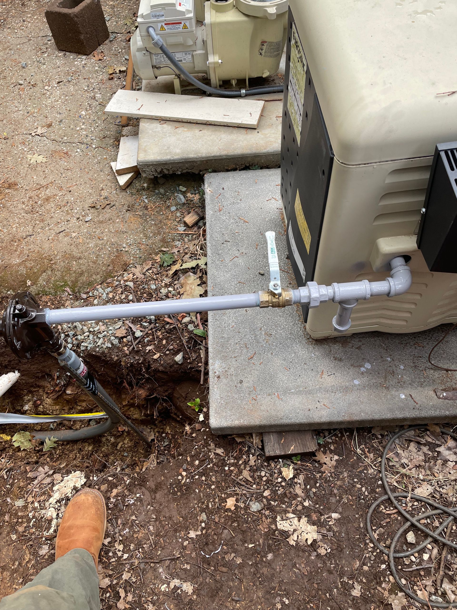 A person is digging a hole in the ground next to a machine.