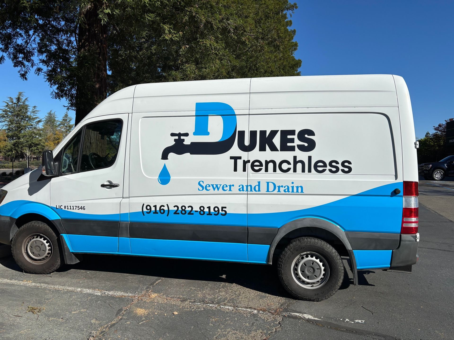 A dukes trenchless sewer and drain van is parked in a parking lot.