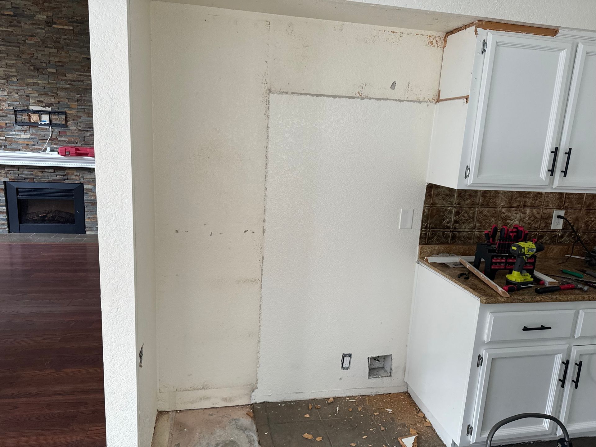A kitchen with white cabinets and a fireplace in the background.