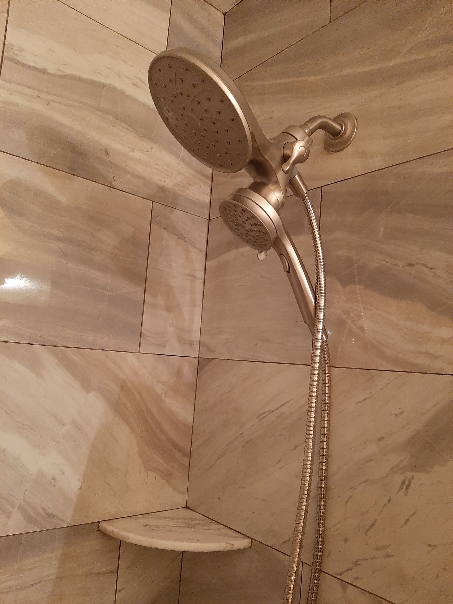 A shower head is hanging on a tiled wall in a bathroom.