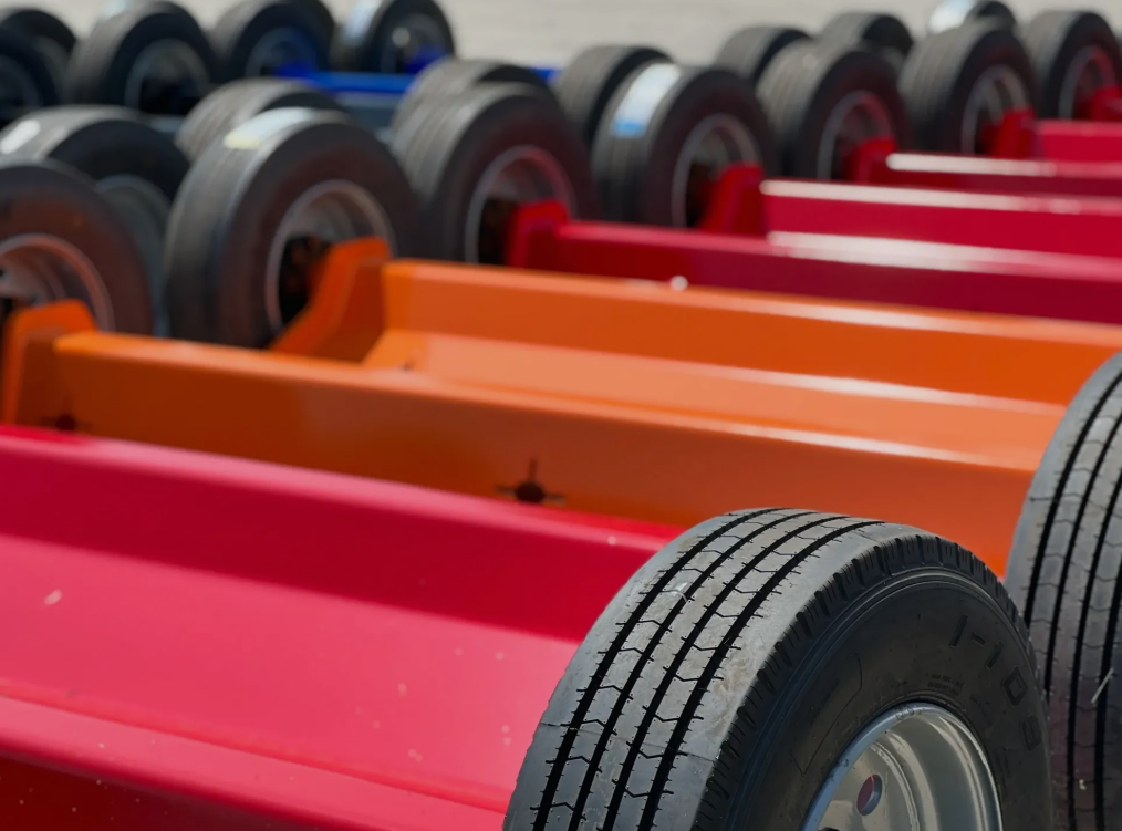 Rows of colorful trailer frames with tires, in red, orange, and blue.