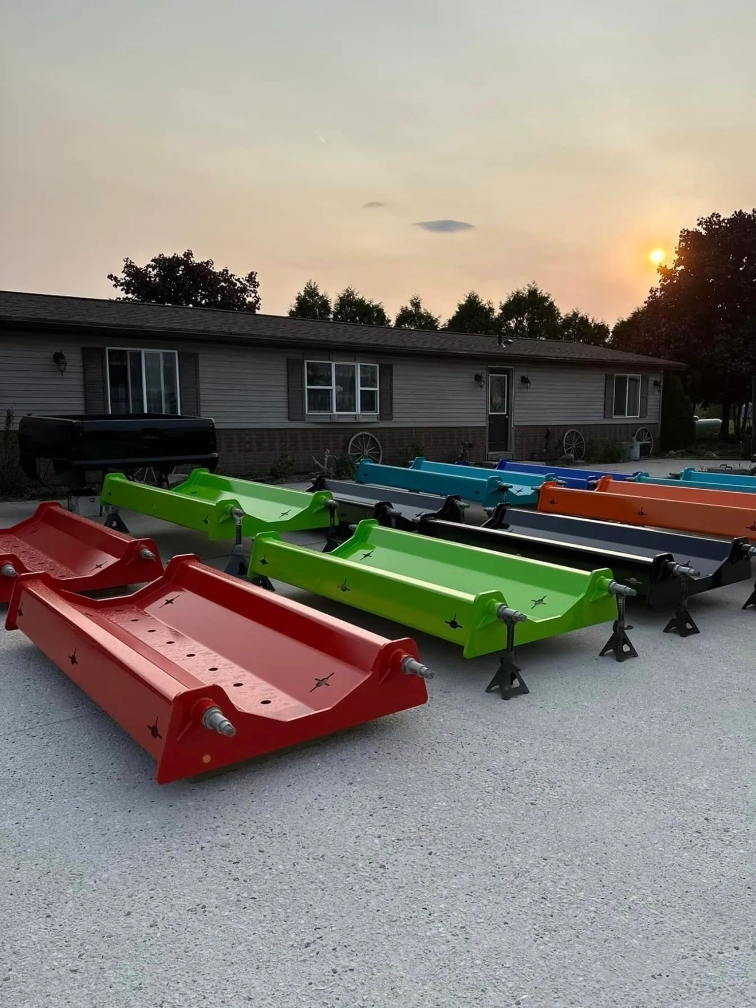 Rows of colorful metal ramps sit on stands in front of a house at sunset.