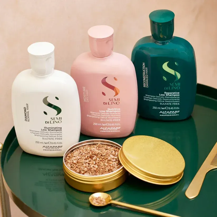 A black and white photo of a hair straightener, brush, and lotion on a bed