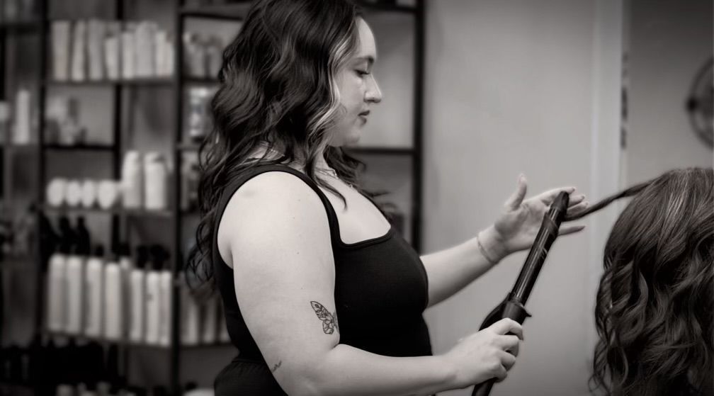 Alyssa is curling another woman 's hair in a salon.