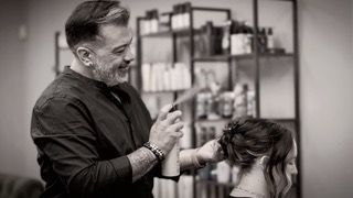 A woman is getting her hair done by a hairdresser in a salon