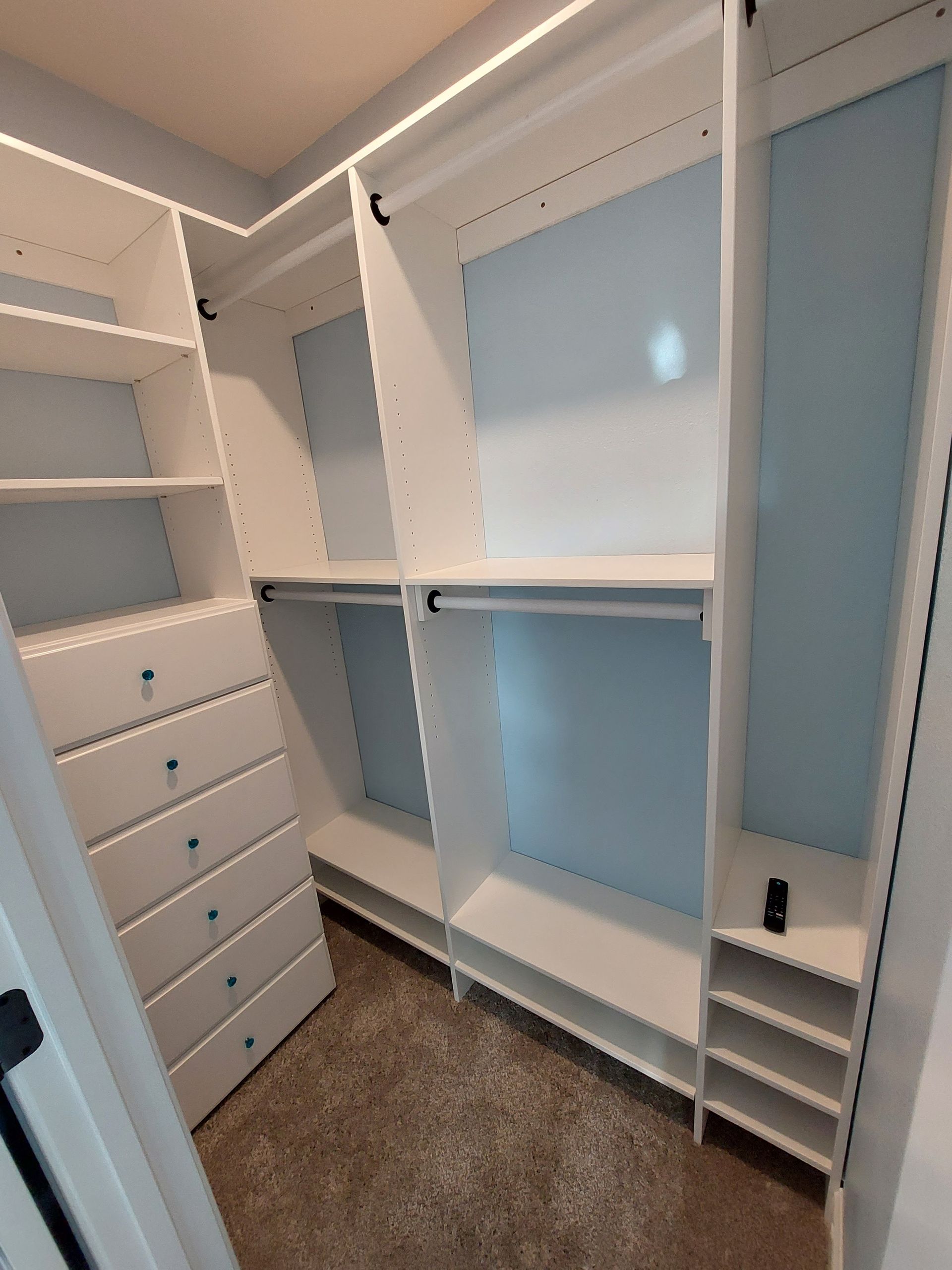 A walk in closet with lots of shelves and drawers