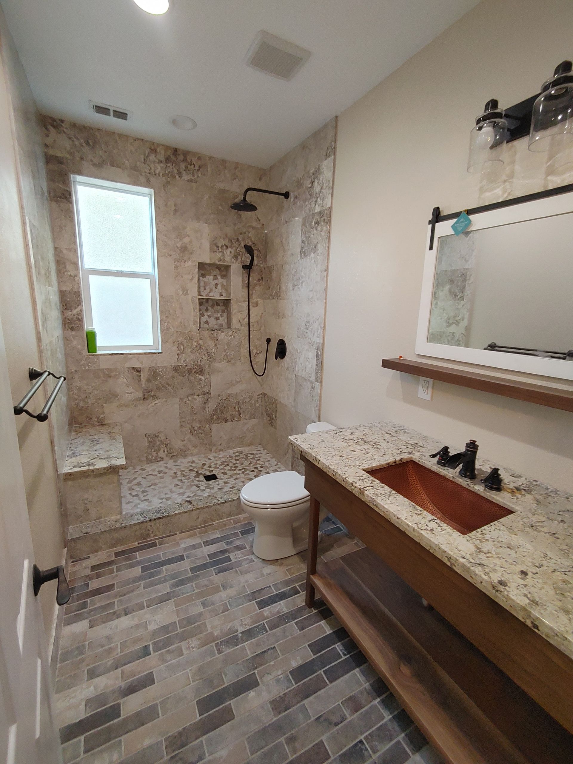 A bathroom with a toilet , sink , shower and mirror.