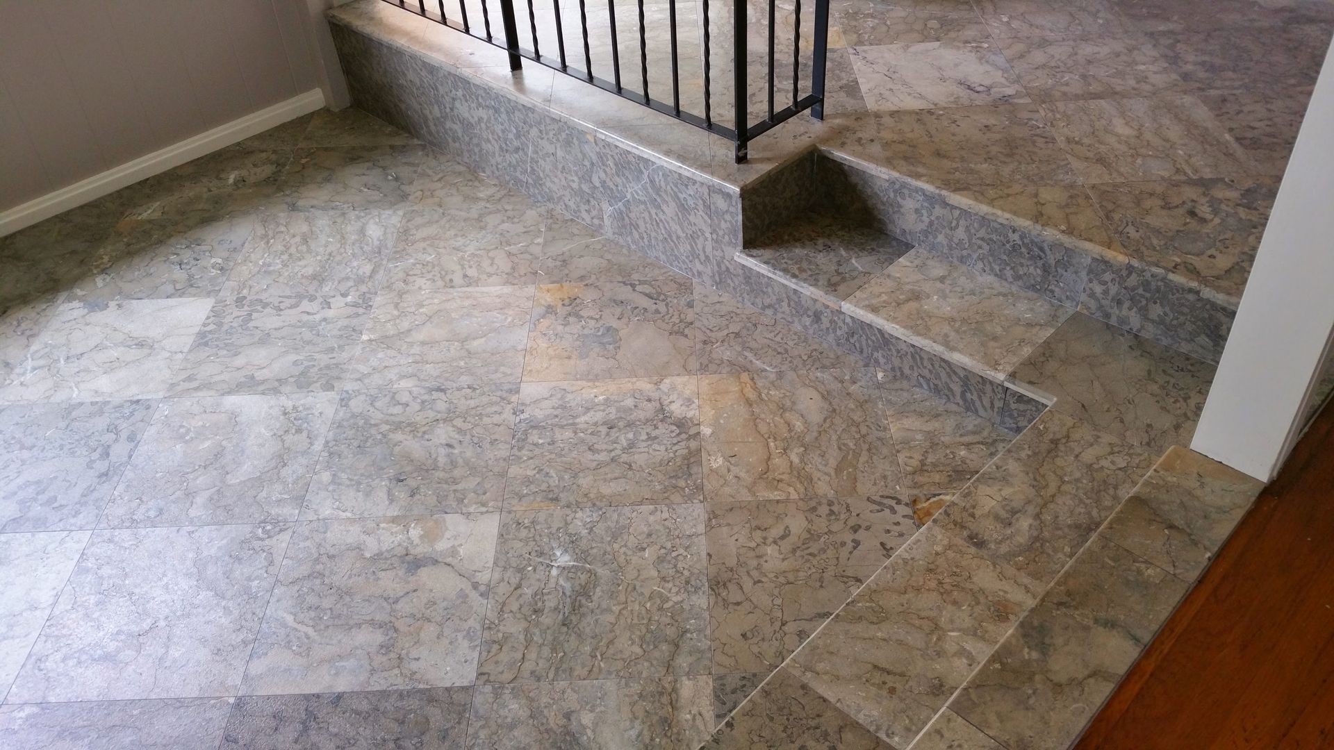 A tiled floor with stairs and a railing in a room.