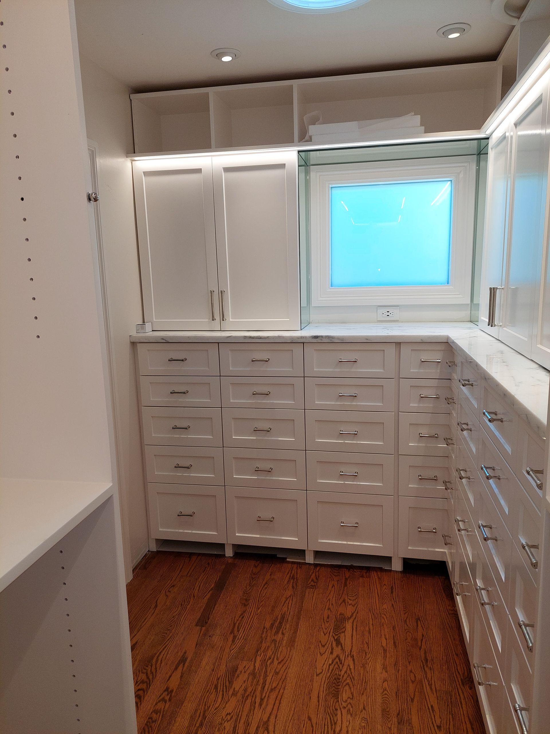 A walk in closet with lots of drawers and a window