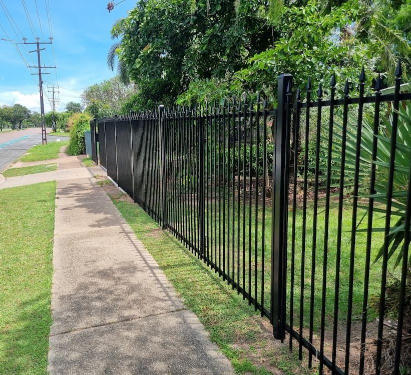 A Black Metal Fence Along A Sidewalk Next to A Road — Fence Factory In Berrimah, NT