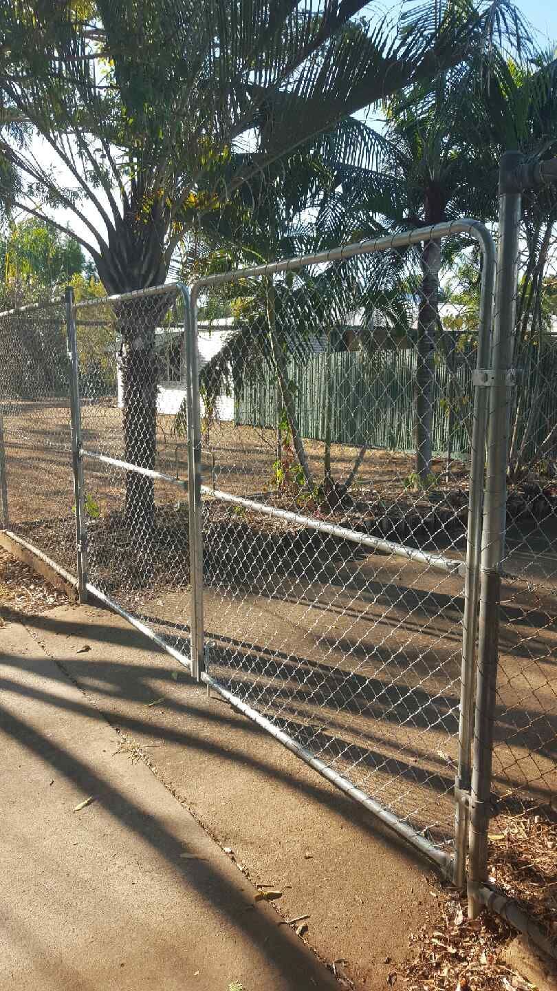 A Chain Link Fence Is Surrounded by A Wooden Fence in A Backyard — Fence Factory In Kununurra, WA
