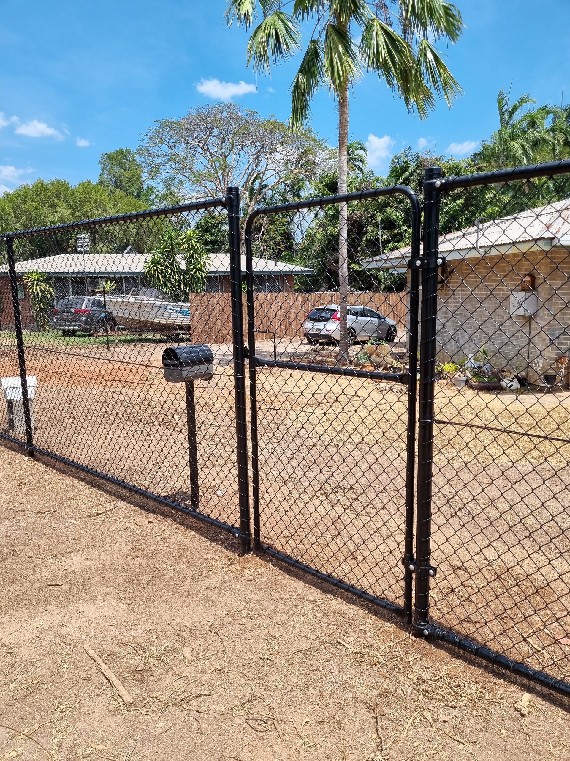 A Chain Link Fence with A single Gate in Front of A House — Fence Factory In Berrimah, NT