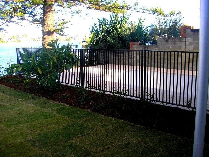 A black fence Surrounds A house — Fence Factory In Palmerston, NT