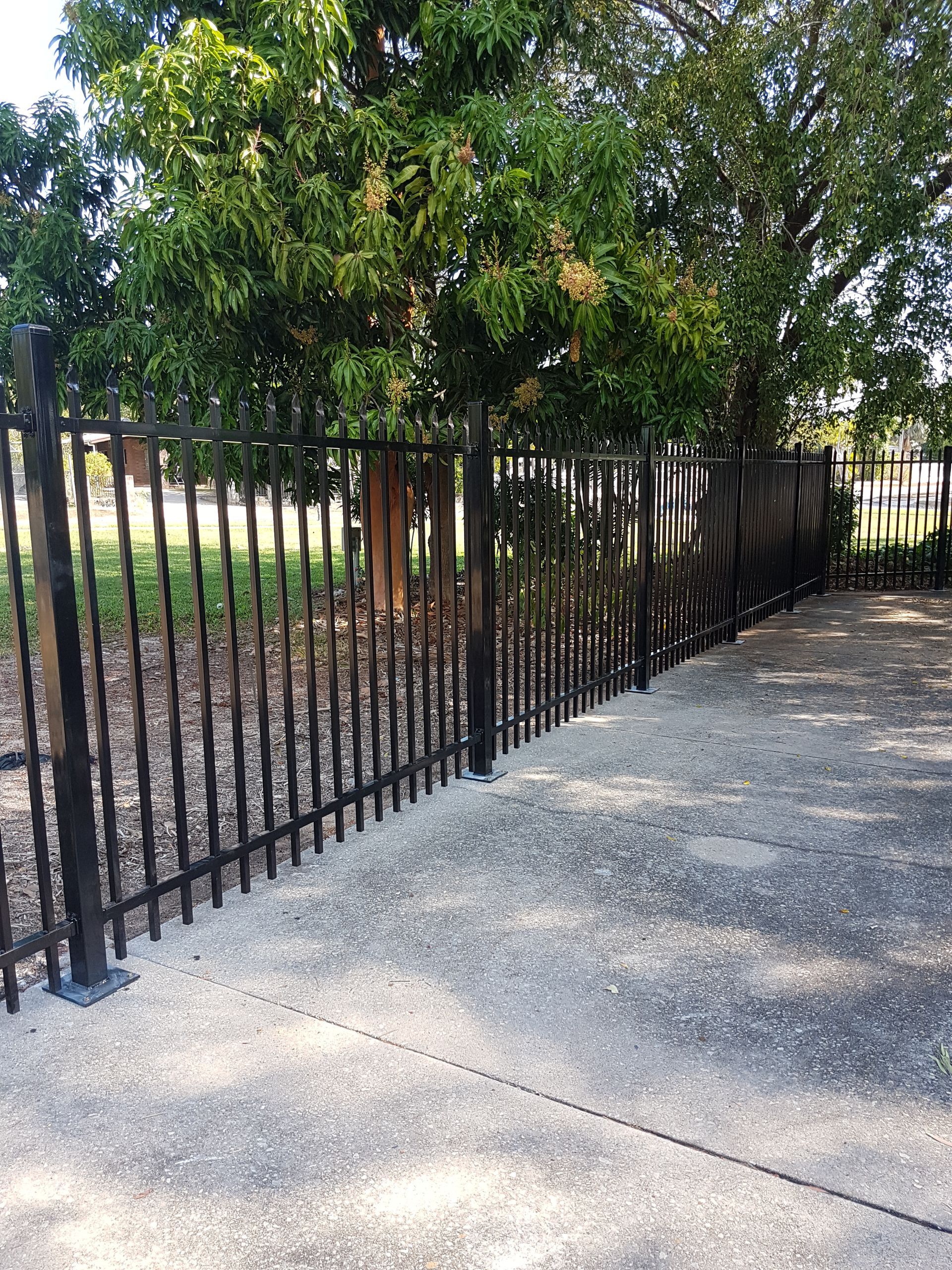 A Black Metal Fence Surrounds a Concrete Walkway in a Park — Fence Factory in Berrimah, NT
